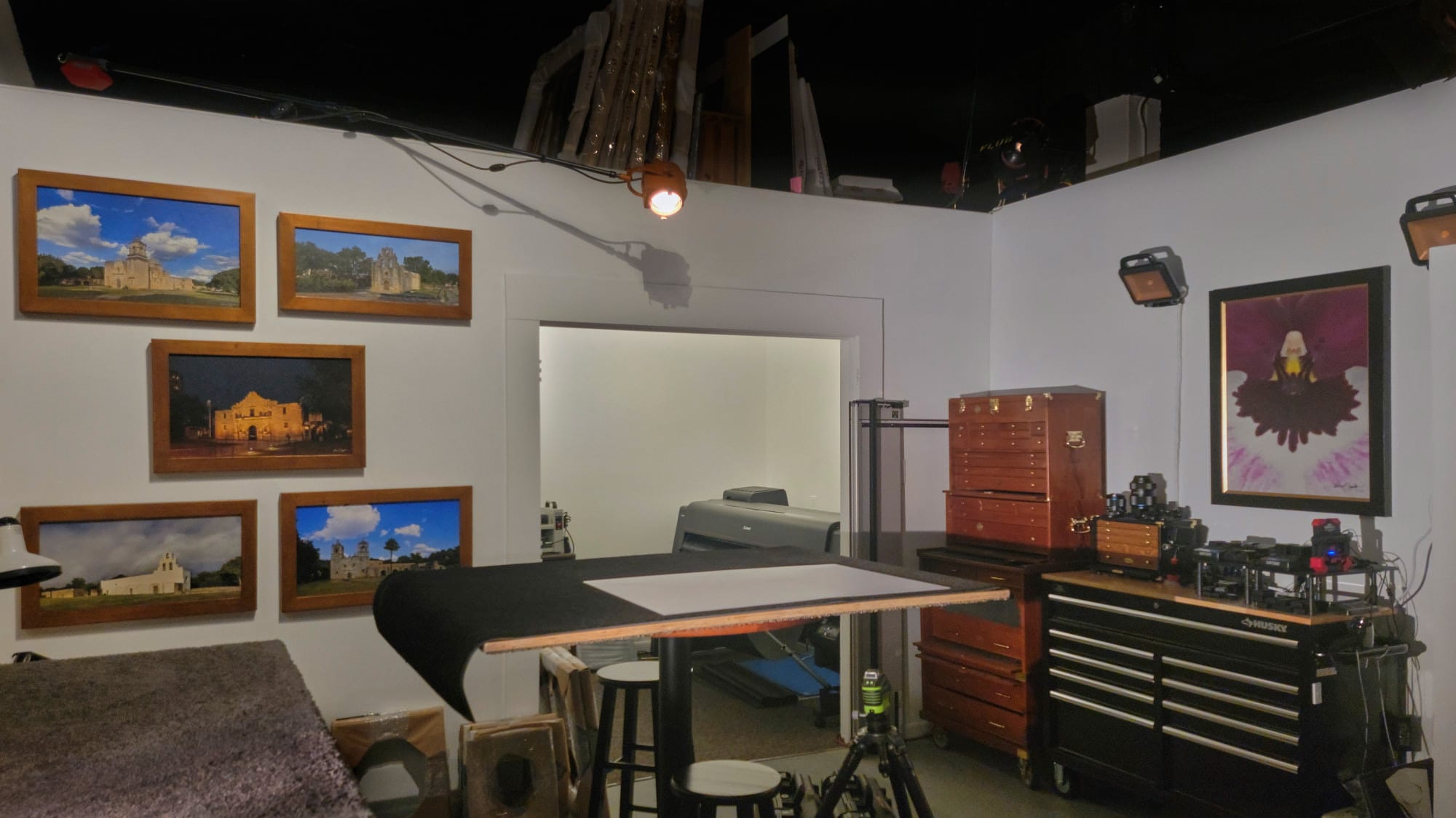 The in-house artist atelier at KGS Studios, showing the custom print framing and coating table, tool chests, and the World Heritage Missions Collection in 