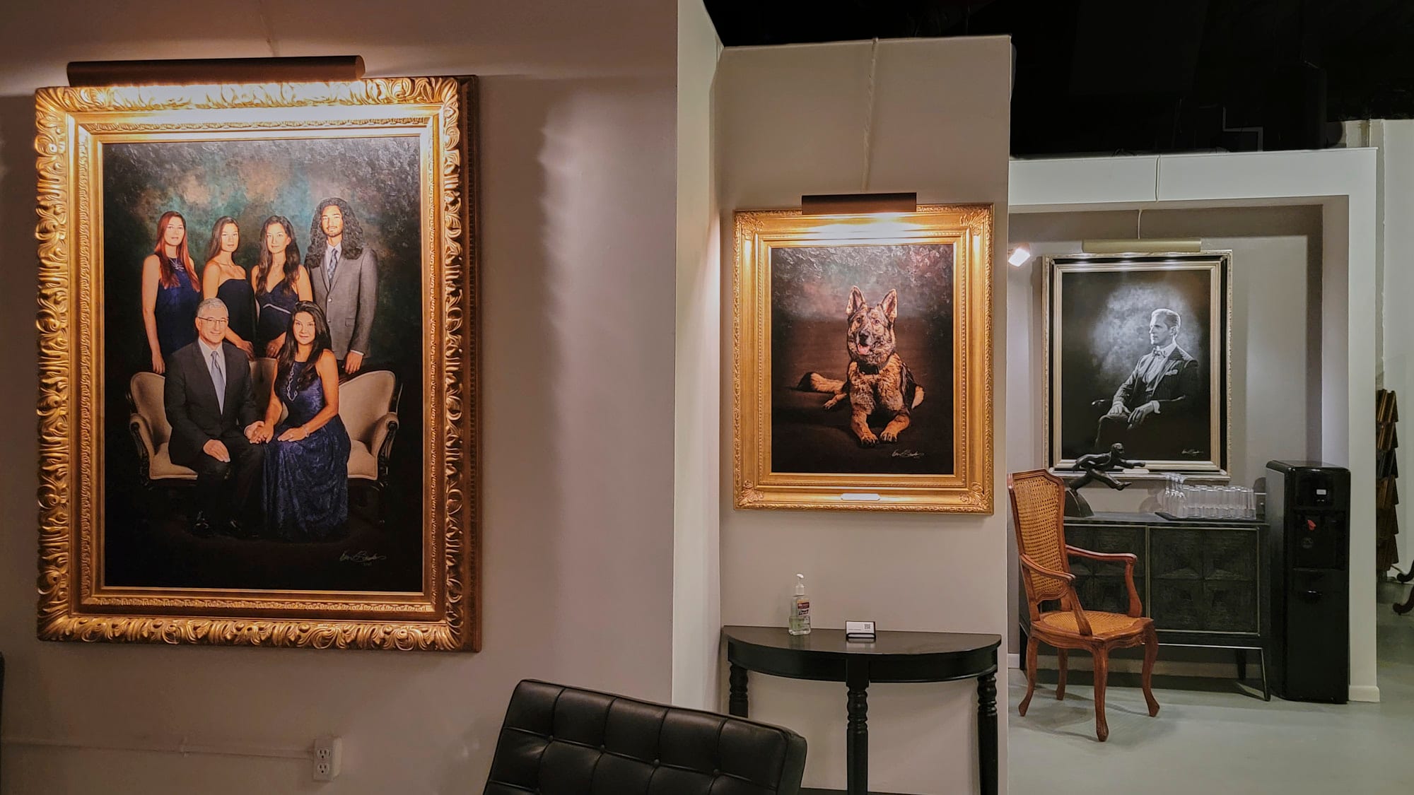 A gallery wall at KGS Studios featuring a large family Statement Piece, a portrait of a German Shepherd, and a black and white portrait of a man.