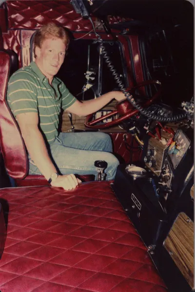 A young Kevin G. Saunders in the cab of his Freightliner truck in the 1981.