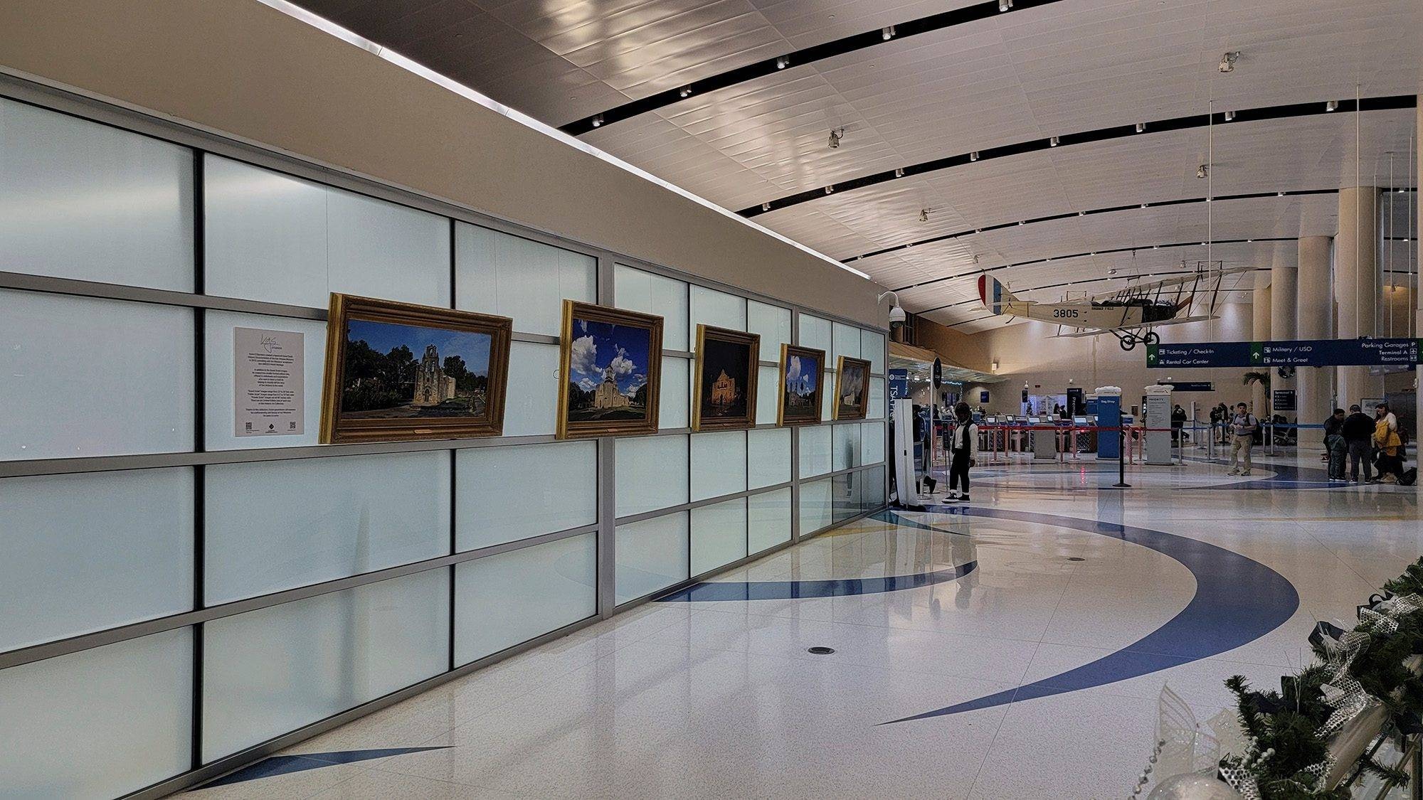 The complete KGS Studios World Heritage Missions Collection, featuring five framed fine art pieces, on public display as a gallery wall in the main concourse of the San Antonio International Airport.